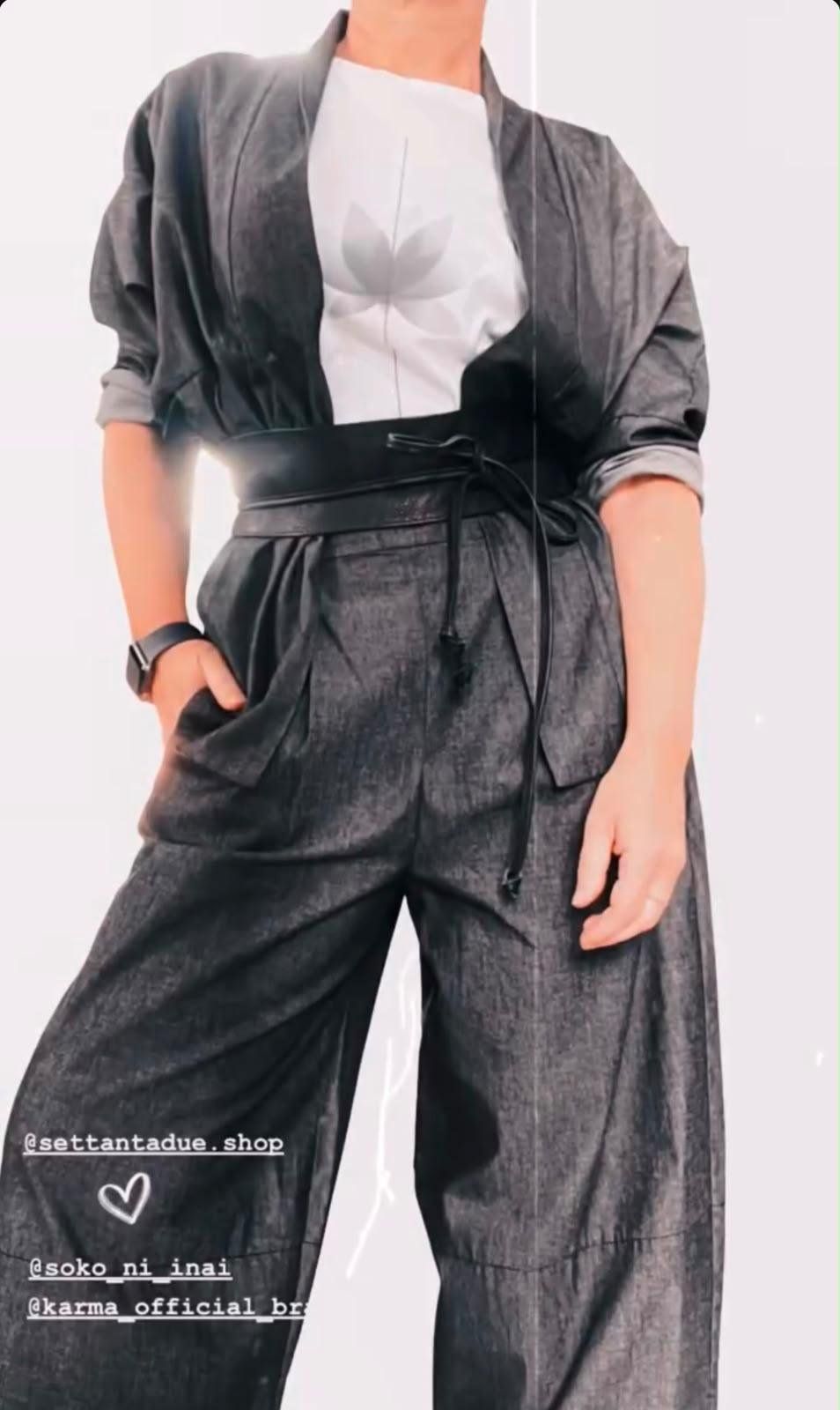 Giacca kimono grigia con maniche arrotolate, t-shirt bianca, cintura obi in pelle nera e pantaloni ampi in tessuto grigio.