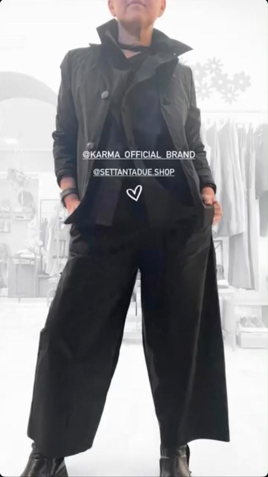 Capospalla nero dal collo alto e pantalone a gamba larga, fotografati in negozio.